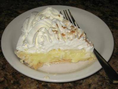 Bluebonnet Cafe Coconut Cream Pie

1 Cup Sugar 
3 Tbsp of Butter or Margarine
1/4 Cup Cornstarch 
1-1/2 Tsp Vanilla
1/4 Tsp Salt 
1 (3-1/2 oz.) Can Flaked Coconut
3 Cups Milk 
4 Eggs, Separated
Your favorite pie crust, baked in a 9-inch pan
Your favorite whipped cream

Separate the egg yolks from the egg whites. Reserve egg whites for a meringue topping or discard.

Combine sugar, cornstarch, salt and milk. Cook mixture over medium to low heat, stirring constantly. After mixture bubbles ups and thickens, cook an additional 2 minutes. Remove from heat.

Beat egg yolks slightly. Gradually stir 1 cup of hot mixture into yolks, being careful not to scramble the yolks. Return the egg mixture to saucepan; bring to a gentle boil. Cook and stir 2 minutes more. Remove from heat.

Add butter and vanilla; stir until butter is melted. Add the coconut and mix. Pour mixture into a baked 9-inch pie crust. Allow pie mixture to cool. 

Top with whipped cream or:

Meringue

4 egg whites, reserved from coconut filling 
1/2 tsp vanilla
1/2 Cup sugar 
1/4 tsp cream of tartar 
toasted coconut flakes

Beat egg whites (at room temperature) and cream of tartar with an electric mixer at high speed. Beat until foamy. Gradually add sugar, 1 tablespoon at a time, until stiff peaks form and the sugar is dissolved (2 to 4 minutes).

Beat in vanilla and spread meringue over hot coconut filling, sealing to the edge of the pastry. Sprinkle extra coconut on top of meringue. Bake at 350 degrees for 12 to 15 minutes or until browned. Allow pie to cool completely before cutting.

Photo: Road Food