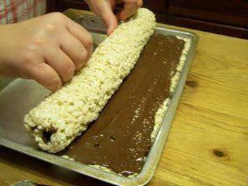 Rice Krispies Rollups

¼ cup butter, melted
10½ ounces mini marshmallows
5½ cups Rice Krispies
1½ cups milk chocolate chips
½ cup peanut butter

Melt butter in a 6 quart kettle,add marshmallows. Melt completely over low heat. Add the Rice Krispies.
Mix well. Spread evenly into a greased 10½ x 15½ baking sheet. In a microwave safe bowl combine chocolate chips and peanut butter. Melt at 1 minute intervals until completely melted, stirring after each minute. Spread on top of Rice Krispies mixture. Let set in a cool place till chocolate mixture sets up. Be careful not to let the chocolate get too hard, it will not make a neat roll if you do.

Loosen all around with a metal spatula. Roll, starting on the long side. Sprinkle the roll with seasonal sprinkles if desired. Slice and enjoy! Can be wrapped in Saran Wrap for storage if needed.
